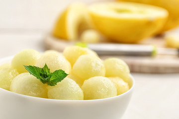 Bowl of melon balls with mint on table, closeup