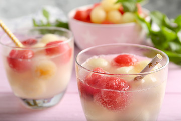 Glasses of melon and watermelon ball cocktail on pink wooden table, closeup