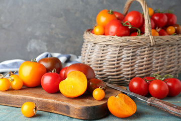 Composition with fresh ripe tomatoes and wicker basket on wooden table