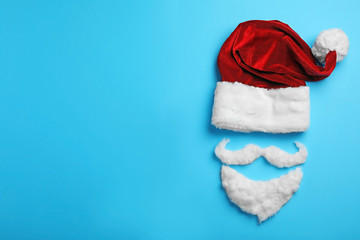Santa Claus hat and beard on light blue background, flat lay. Space for text