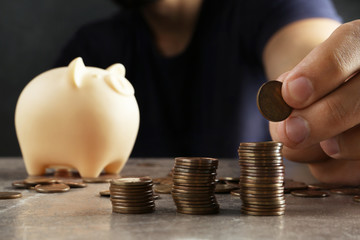 Man stacking coins on brown marble table, closeup