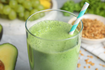 Glass of tasty avocado smoothie with straw on table, closeup