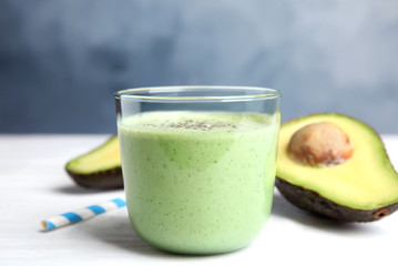 Glass of tasty avocado smoothie with chia seeds on white wooden table
