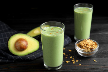 Glasses of tasty smoothie with avocado and oatmeal on black wooden table