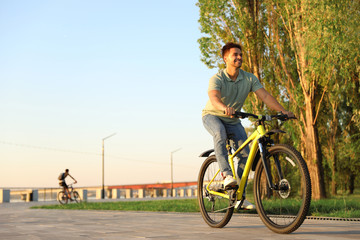 Handsome young man riding bicycle on city waterfront