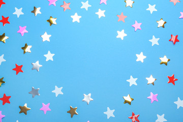 Frame of confetti stars with space for text on blue background, top view. Christmas celebration