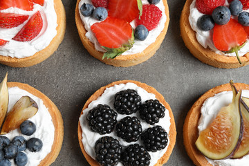 Different berry tarts on grey table, flat lay. Delicious pastries