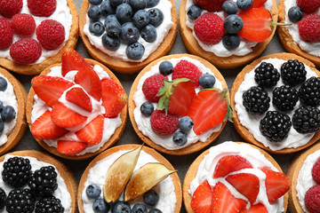 Many different berry tarts on table, top view. Delicious pastries - obrazy, fototapety, plakaty