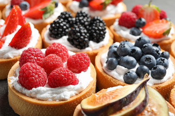 Many different berry tarts on table, closeup. Delicious pastries