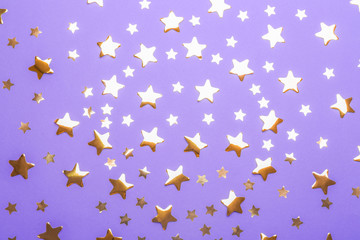 Confetti stars on violet background, flat lay. Christmas celebration