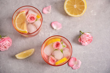 Tasty refreshing lemon drink with roses on light grey table, flat lay
