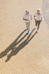 Top view of senior woman and man running doing fitness exercises outdoors