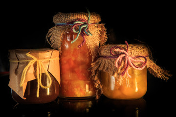 closeup three glass jars of organic jam with rustic decoration