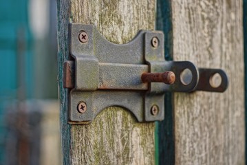 open black metal latch on a gray wooden door board
