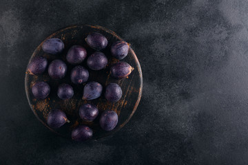 Fresh figs in a bowl on a dark wood background, top view with copy space