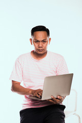 An attractive young man wears a white striped shirt on a pink shirt. Holding a laptop on his hand Internet connection type Stock trading Ordering products online 5g communication system concept