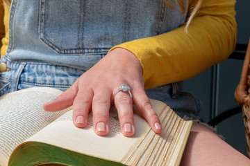 Closeup of hand with diamond ring on vintage book