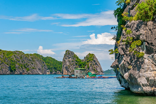 A summer day between the karst mineral formations and emerald waters of the Tonkin Gulf in Halong Bay with a floating house, North Vietnam, Asia.