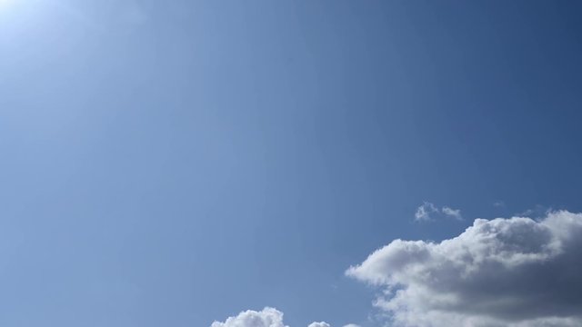 Day to night time-lapse. Clouds are passing through a blue sky.