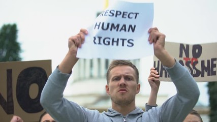 Crowd shouting slogan to respect human rights, no harassment, against violence