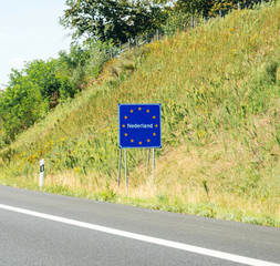 Nederland text at the border between Germany and Netherlands with text on the road sign with European union stars