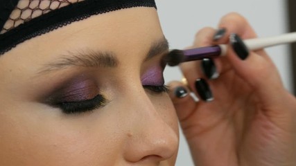 Professional stylist make-up artist makes eye makeup model. Face model with evening make-up close up view