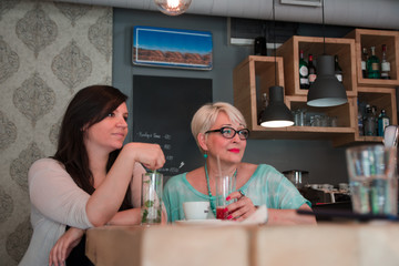 Two cheerful women having fun during coffee time in a cafe