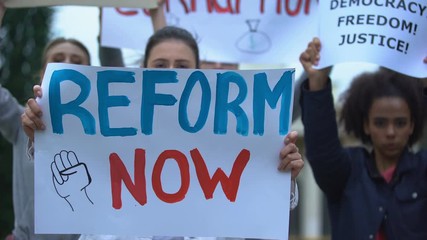 Activist showing banner Reform now, protesting corruption, unfair justice