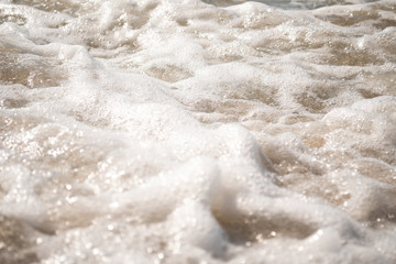 Fototapeta na wymiar Close-up of Foamy Water Over Sand