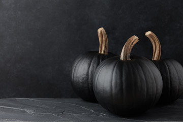 Black pumpkins on black textured background