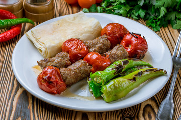 Lula kebab with tomatoes on wooden table Turkish cuisine