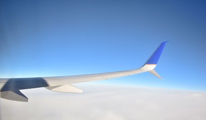 Wing of an airplane flying above the clouds