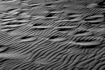 TEXTURE AND FORMS OF BEACH SAND. BLACK AND WHITE PHOTOGRAPHY