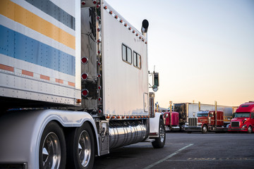 Naklejka premium White big rig bonnet American make semi truck with long sleeping compartment standing on the truck stop opposite another semi trucks