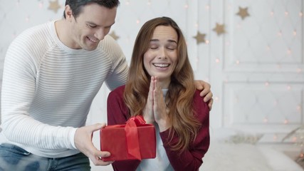 Pretty woman waiting gift with closed eyes in living room.