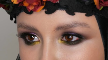 Professional girl model with beautiful makeup poses in a black cap and wreath on her head in front of the camera in the image of a black widow. High-fashion