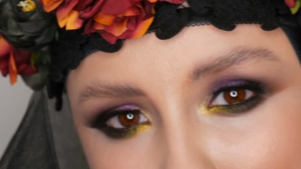 Professional girl model with beautiful makeup poses in a black cap and wreath on her head in front of the camera in the image of a black widow. High-fashion
