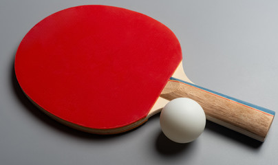 red pingpong racket and ball on a grey background