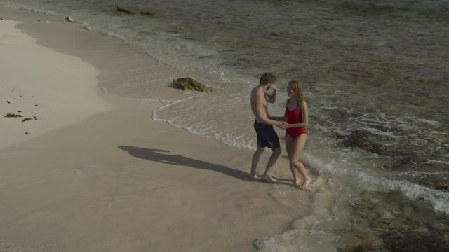 Aerial view of happy couple holding hands and walking on beach / Petit Tabac, Tobago Cays, St. Vincent and the Grenadines