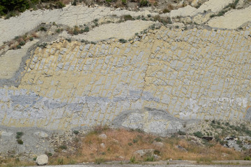 slope of the mountain with layers of sedimentary rocks. Vertically located sedimentary rocks on...