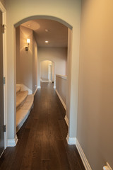 hallway with hardwood floors has arched doorway accents.