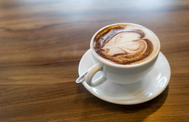 Hot coffee cappuccino latte spiral foam on dark wooden background
