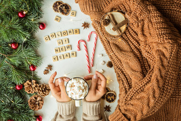 Woman Hands holding cup of Hot Chocolate with marshmallow. Flat lay with Christmas Decorations, Wide Composition, top view, mockup, overhead. Colors of new year phrase .Winter holidays concept
