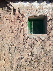 Rustic green window of an agricultural village in the middle of Spain. Construction of the adobe wall, composite materials made of earth mixed with water and an organic material such as straw or dung.