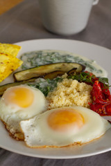 breakfast of fried eggs vegetables and yogurt
