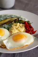 breakfast of fried eggs vegetables and couscous 