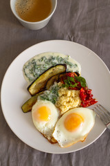 breakfast of fried eggs vegetables and couscous with yogurt