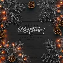 Christmas composition on wooden background. Xmas decoration design, snowflake color black, gold light garland, pine cone. Black realistic Wood texture. Flat lay, top view.