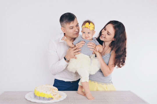 the child in the arms of his mother and father, who was soiled with food. A woman and man with a child in her arms eating cake