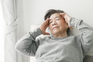 Asian senior woman having headache at home, health care concept.